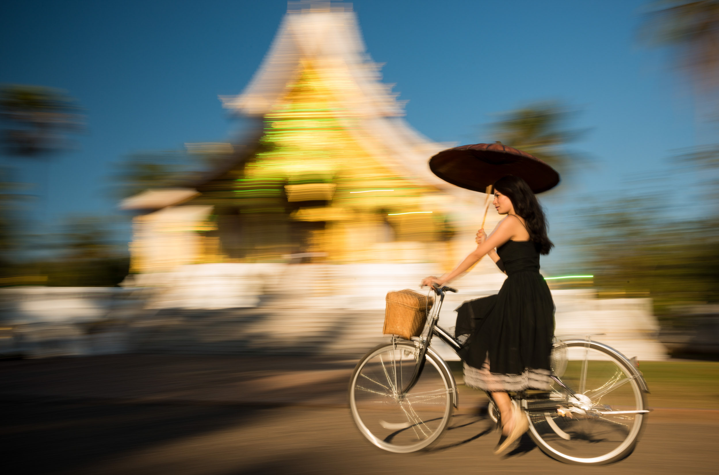 woman-cycling-unbrella-luang-prabang-laos-asia-temple